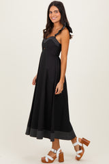 woman wearing a black midi dress with ruffle straps and striped hem, paired with white platform sandals
