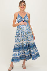 woman wearing a blue floral maternity maxi dress and holding her baby bump