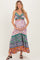 woman wearing a floral print maternity maxi dress with green and orange accents and holding her baby bump