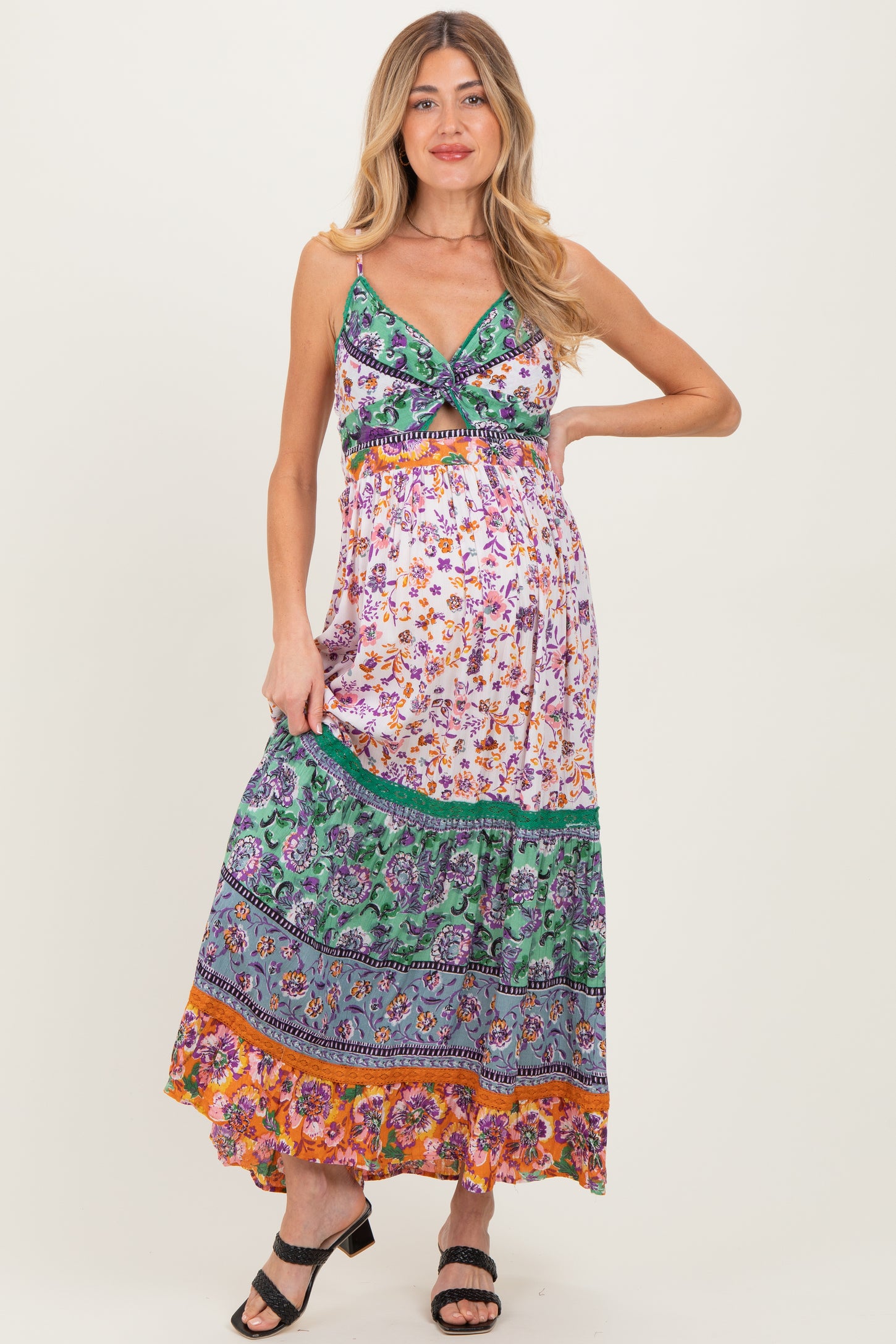 woman wearing a colorful maxi maternity dress with floral patterns and a fitted bodice, showcasing her baby bump