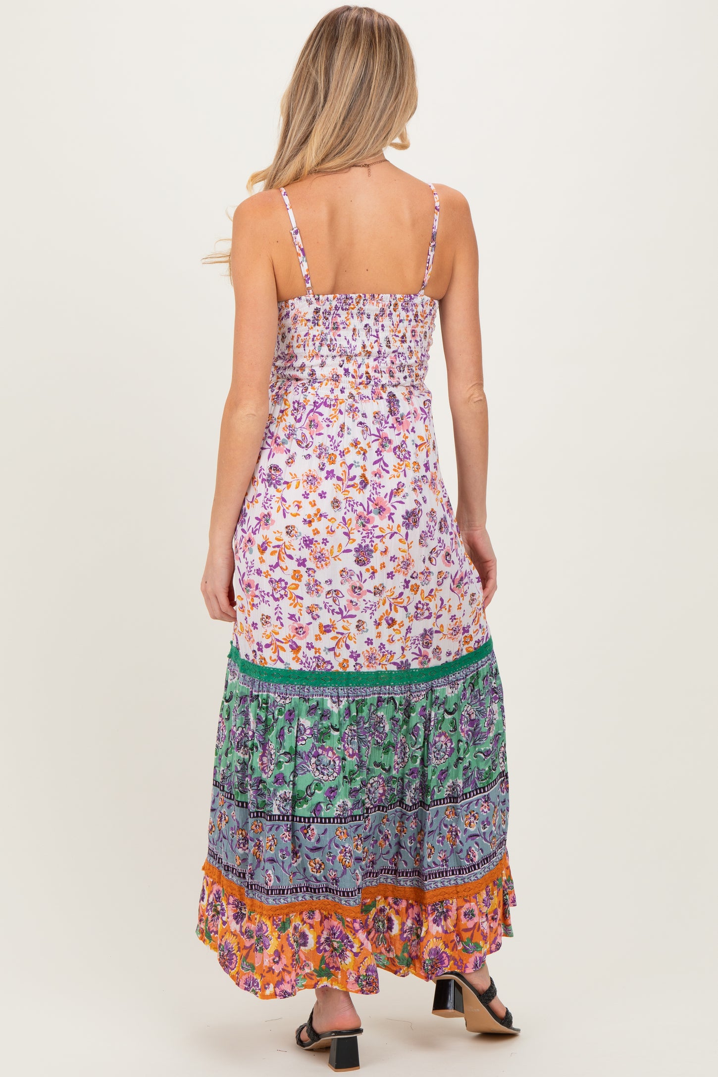 woman wearing a floral print maternity maxi dress with a smocked bodice and colorful tiered skirt, showing a baby bump
