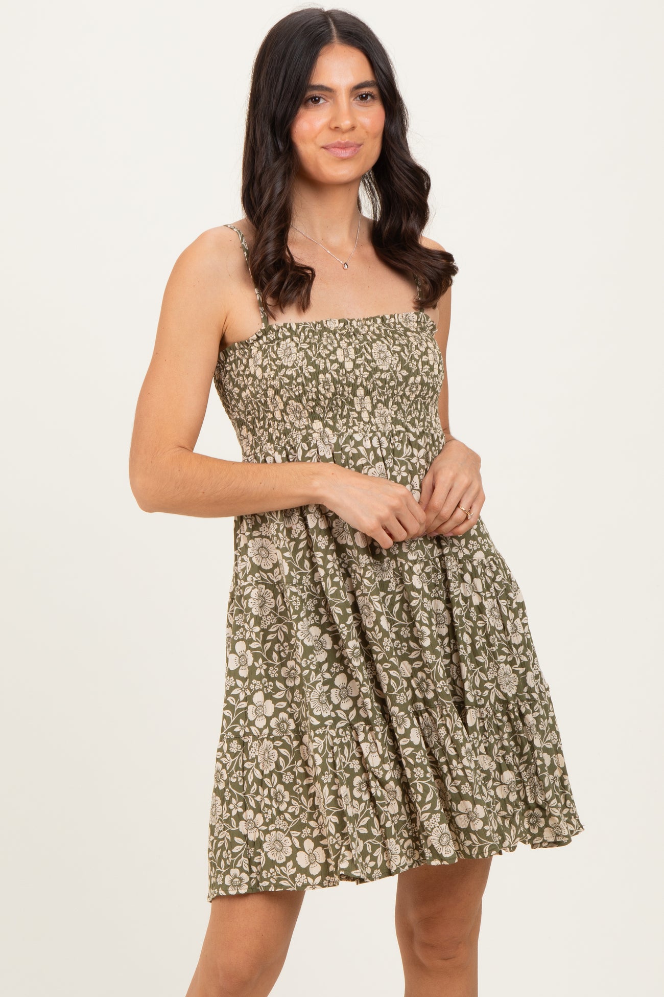 woman wearing a green floral print sundress with a fitted bodice and ruffled skirt