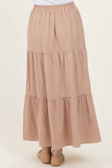 woman wearing a tiered maxi skirt in a brown and cream checked pattern, featuring an elastic waistband and flowing style