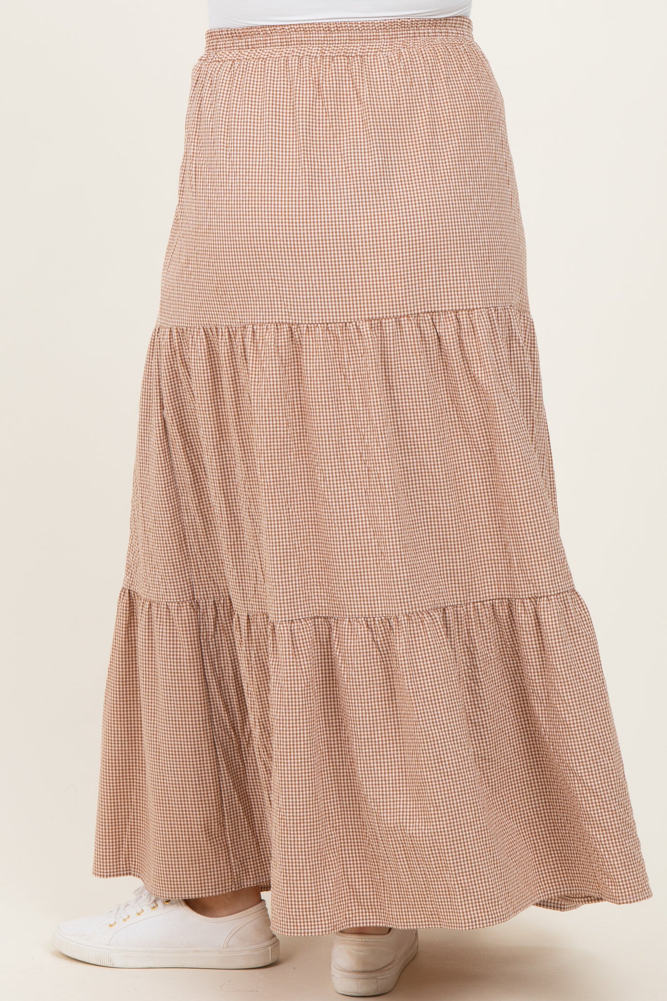 woman wearing a checkered brown maternity maxi skirt with a tiered design and elastic waistband