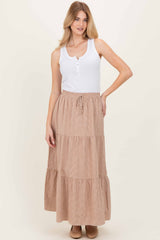 woman wearing a white sleeveless henley top and a tan striped maxi skirt with tiered layers