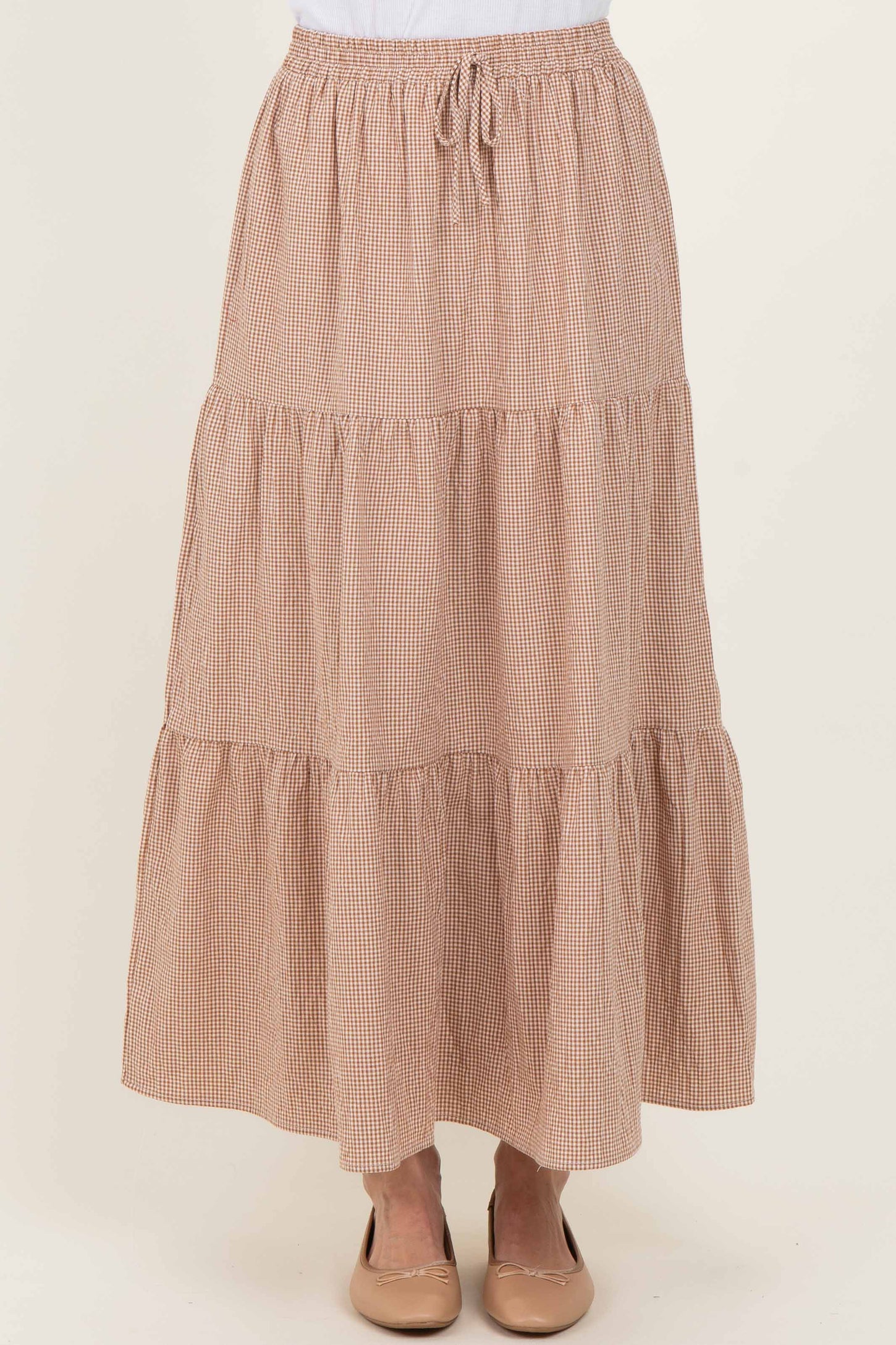 woman wearing a brown and white checked tiered maxi skirt with an elastic waistband and drawstring detail
