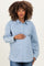 woman wearing a light blue striped maternity button-up shirt and holding her baby bump