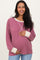 woman wearing a mauve striped maternity sweater with cream sleeves and holding her baby bump