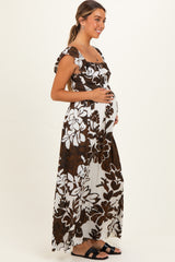 woman wearing a brown and white floral maternity maxi dress and holding her baby bump