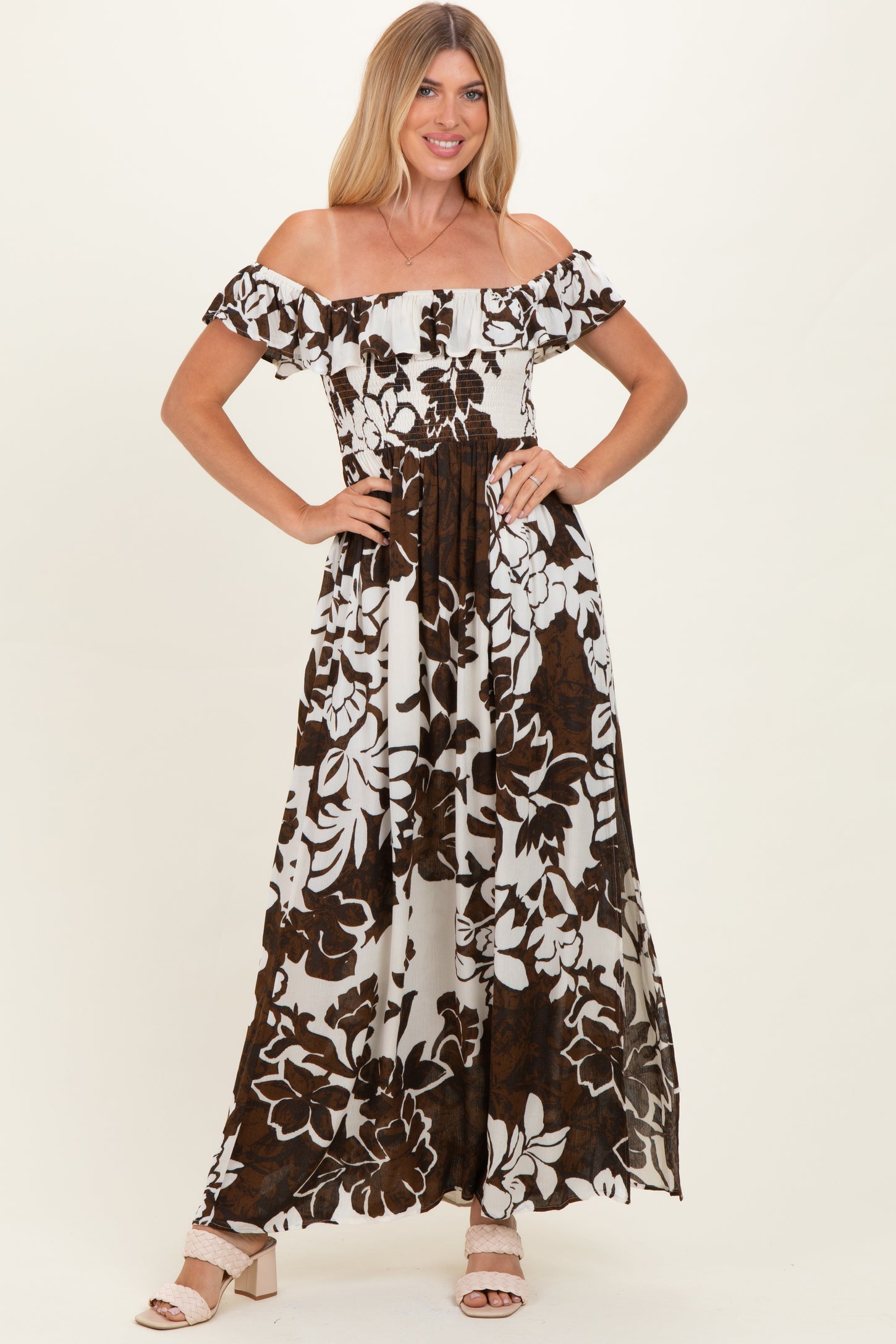 woman wearing a brown and white floral off-shoulder maxi dress standing with hands on hips