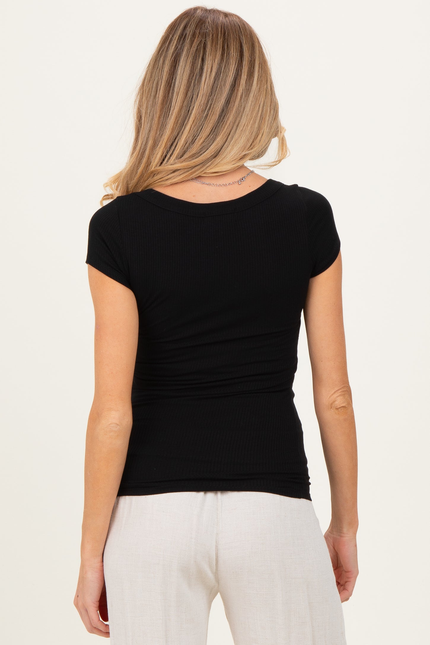 woman wearing a black short sleeve fitted maternity top with ruching at the back
