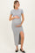 woman wearing a light gray ribbed maternity maxi dress with a side slit and holding her baby bump