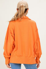 woman wearing an oversized orange maternity sweatshirt with a collar and relaxed fit, seen from the back