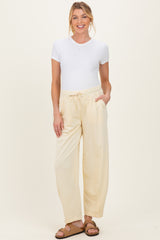 woman wearing a white short sleeve v-neck top and cream maternity pants with pockets and an elastic waistband