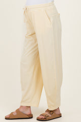 woman wearing light yellow maternity loungewear pants with side pockets and a drawstring waist