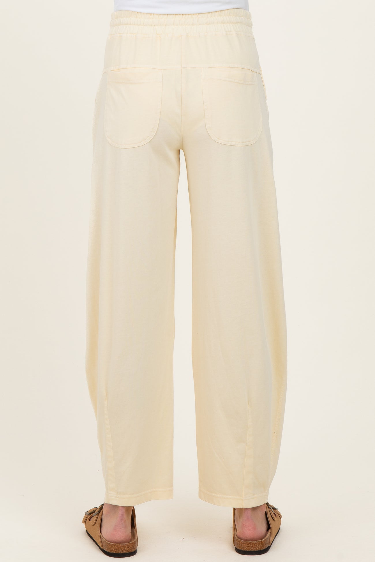 maternity wear in light cream wide-leg pants with a comfortable waistband and back pockets, model shown from the back