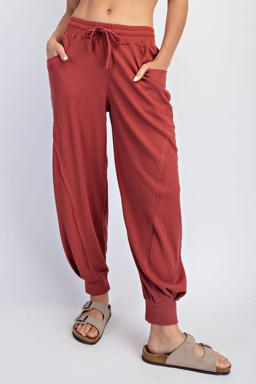 woman wearing rust-colored ribbed jogger pants with drawstring waist and side pockets