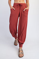 woman wearing rust-colored ribbed harem pants with pockets and drawstring waist, paired with casual sandals