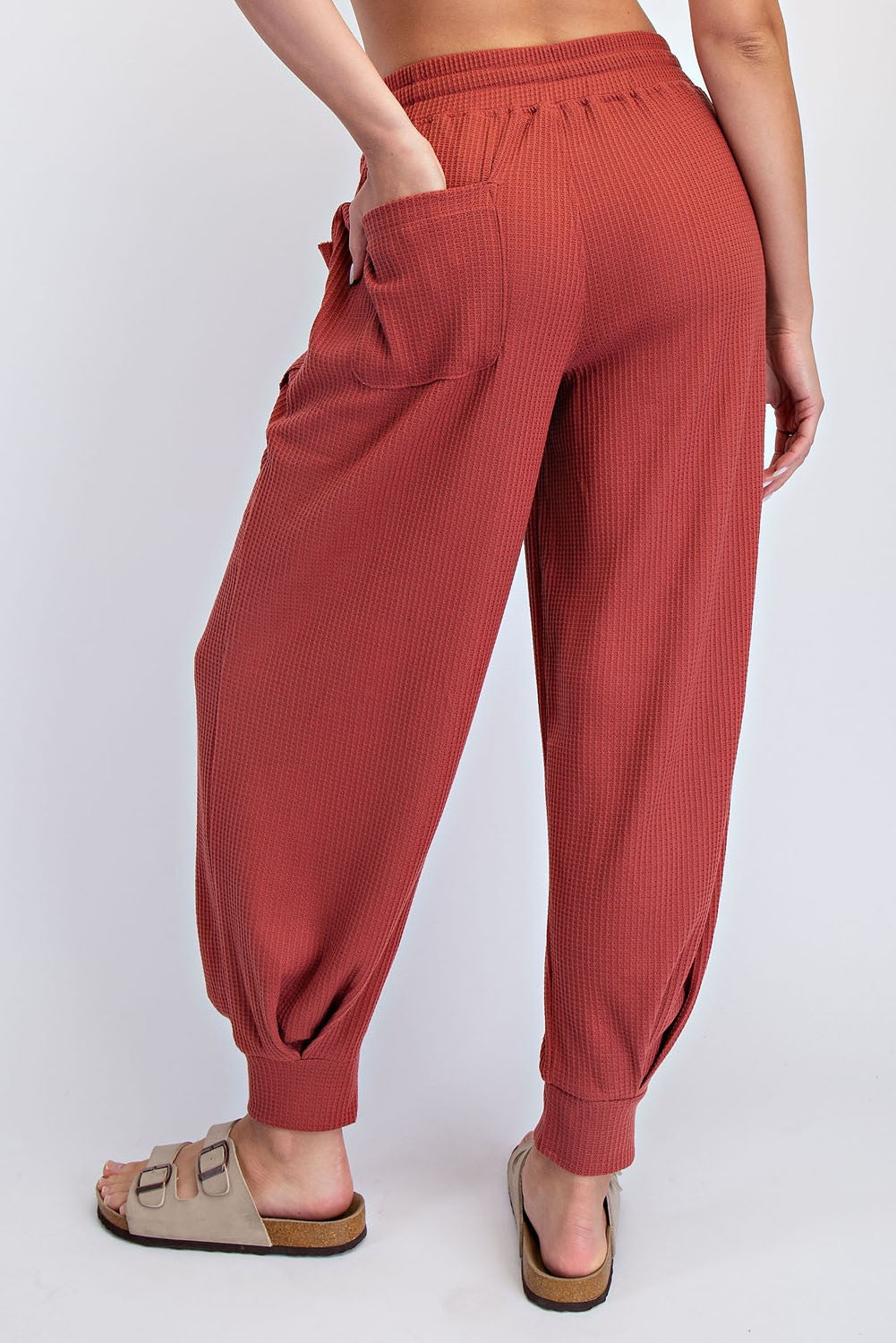 woman wearing rust-colored ribbed lounge pants with side pockets and tapered cuffs