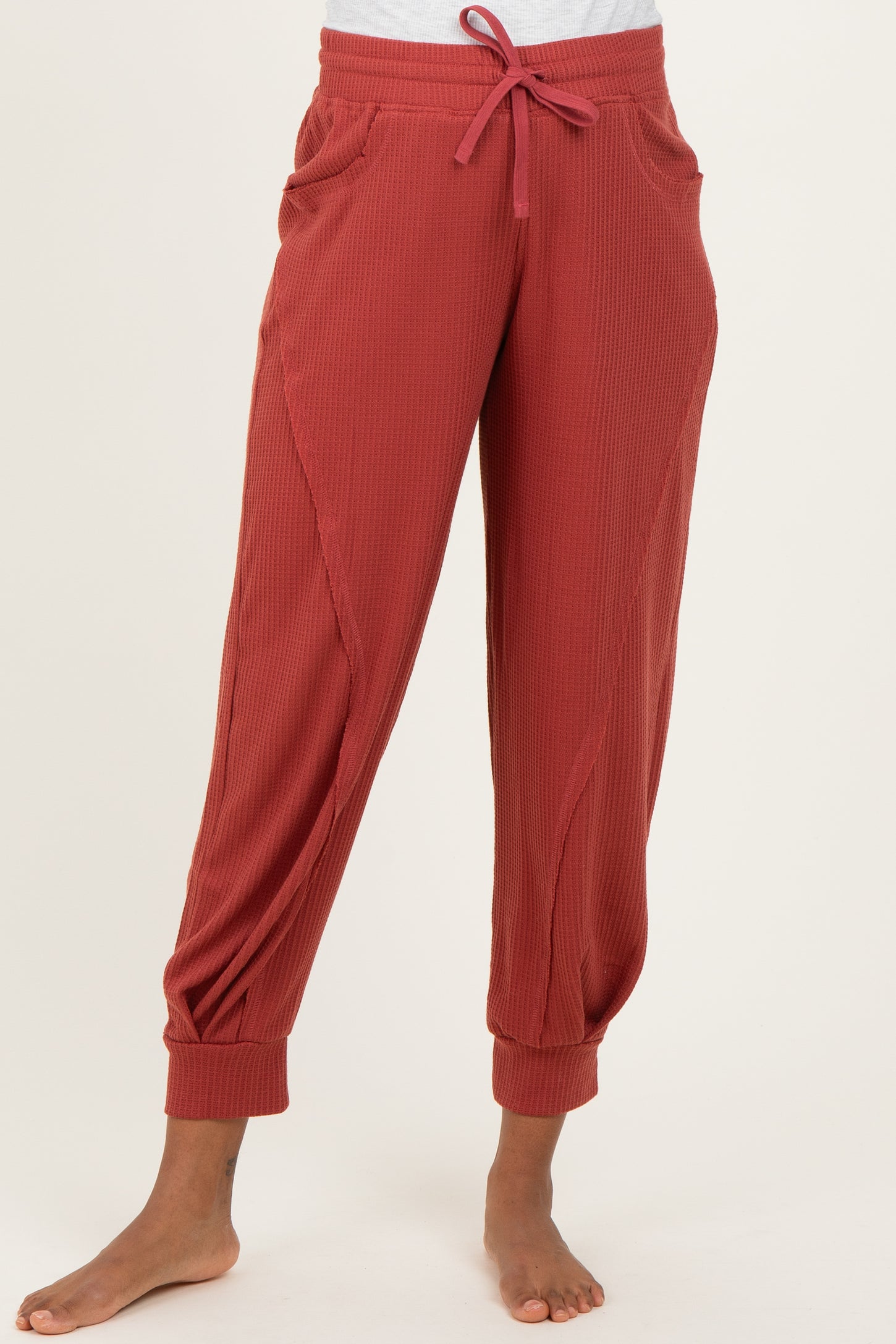 woman wearing rust-colored maternity jogger pants with a drawstring waist and side pockets