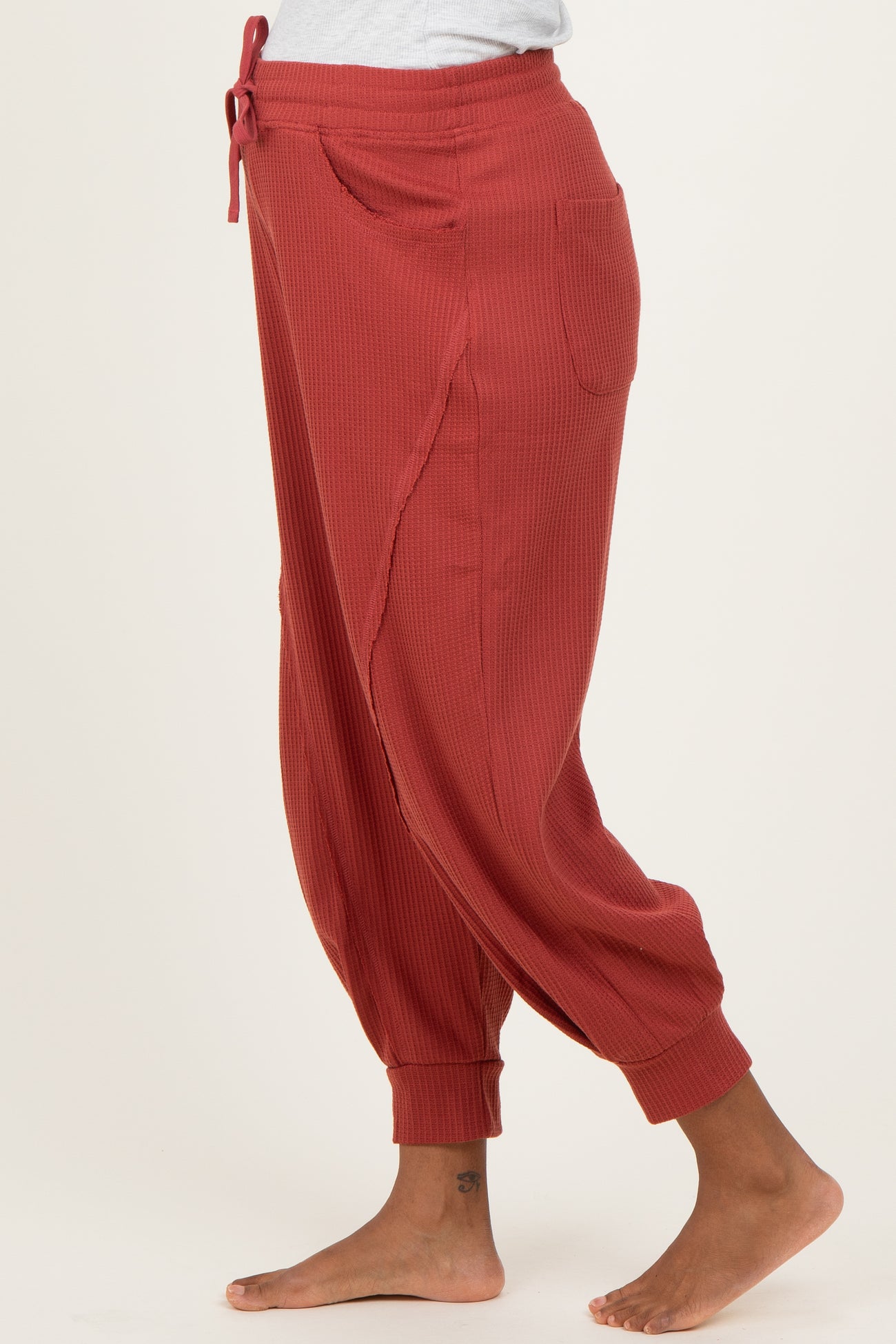 woman wearing a rust-colored ribbed maternity jogger pants with pockets and a relaxed fit