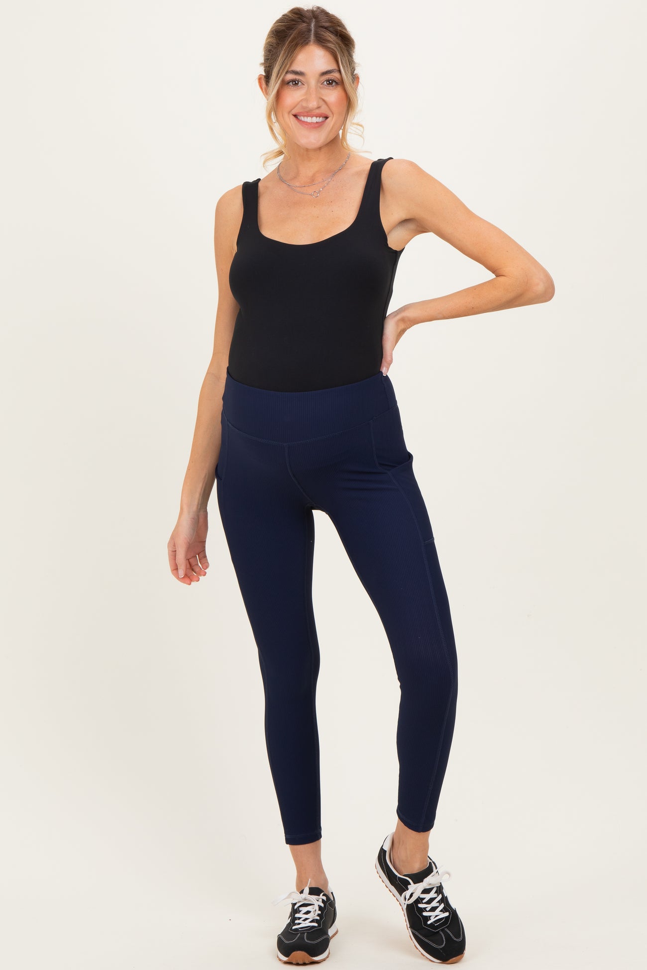 woman wearing a black maternity bodysuit and navy ribbed maternity leggings with pockets