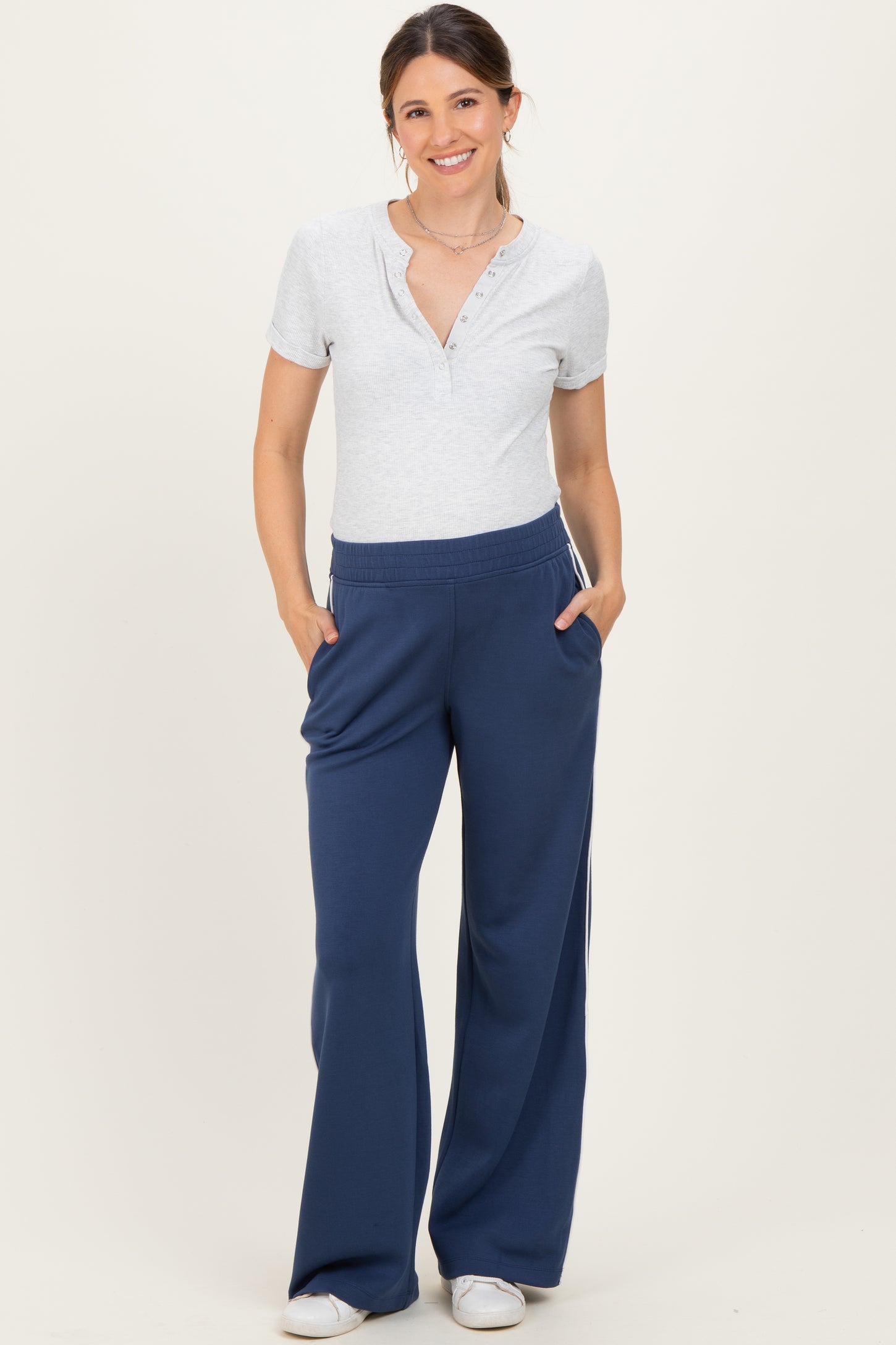woman wearing a gray short sleeve henley top and navy blue maternity sweatpants with pockets