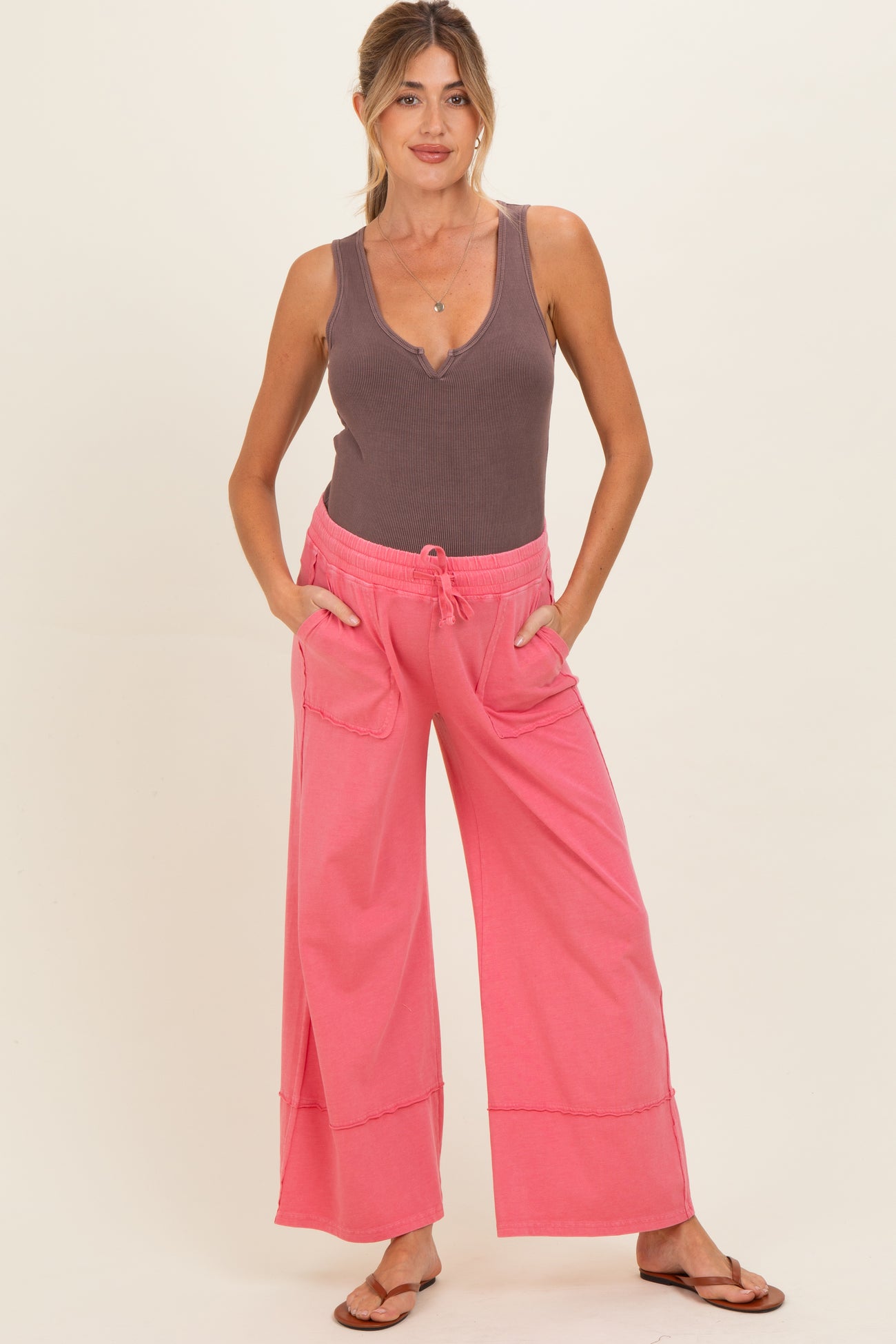 woman wearing a brown ribbed maternity tank top and coral pink wide-leg maternity pants with pockets