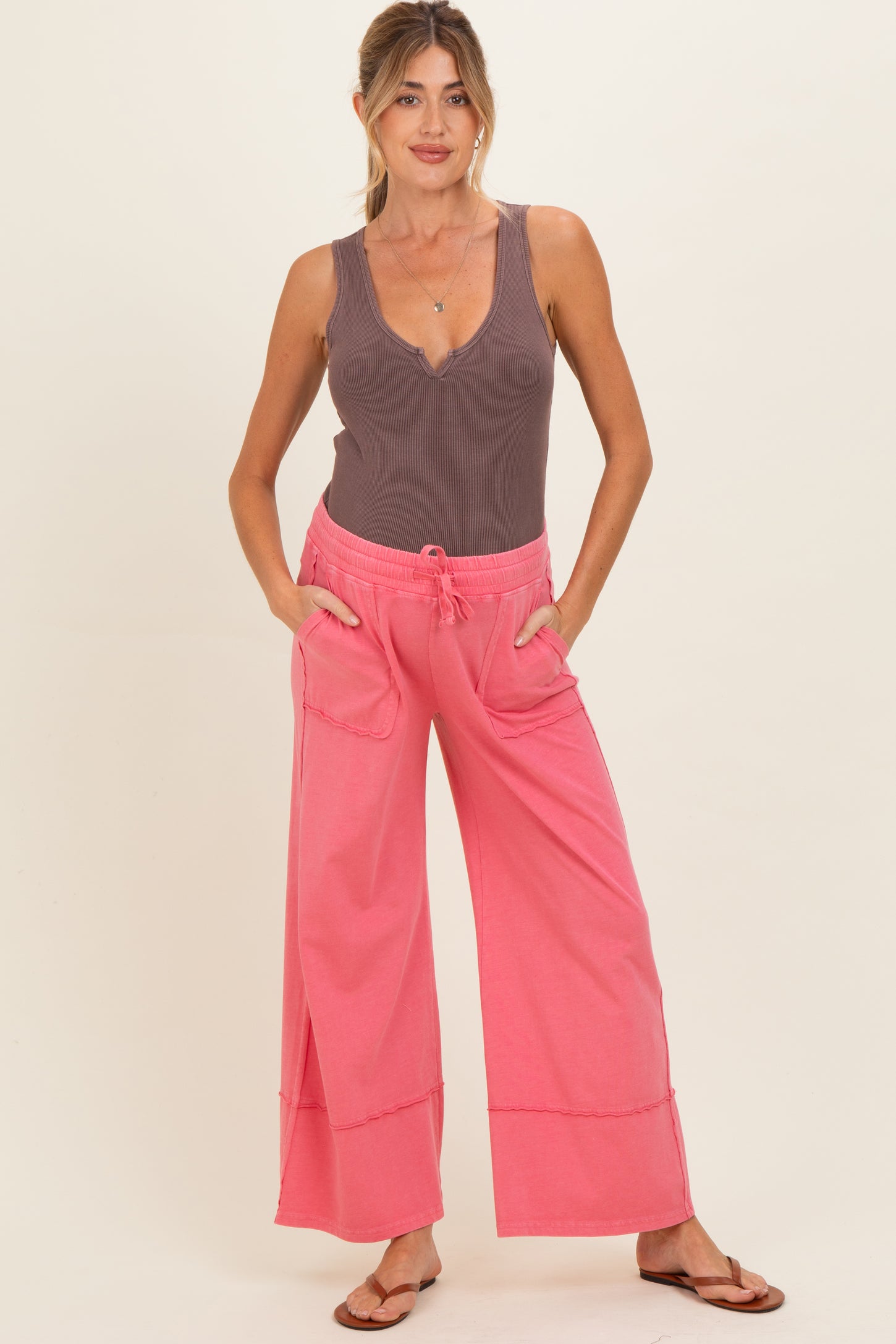 woman wearing a brown ribbed maternity tank top and coral pink wide-leg maternity pants with pockets