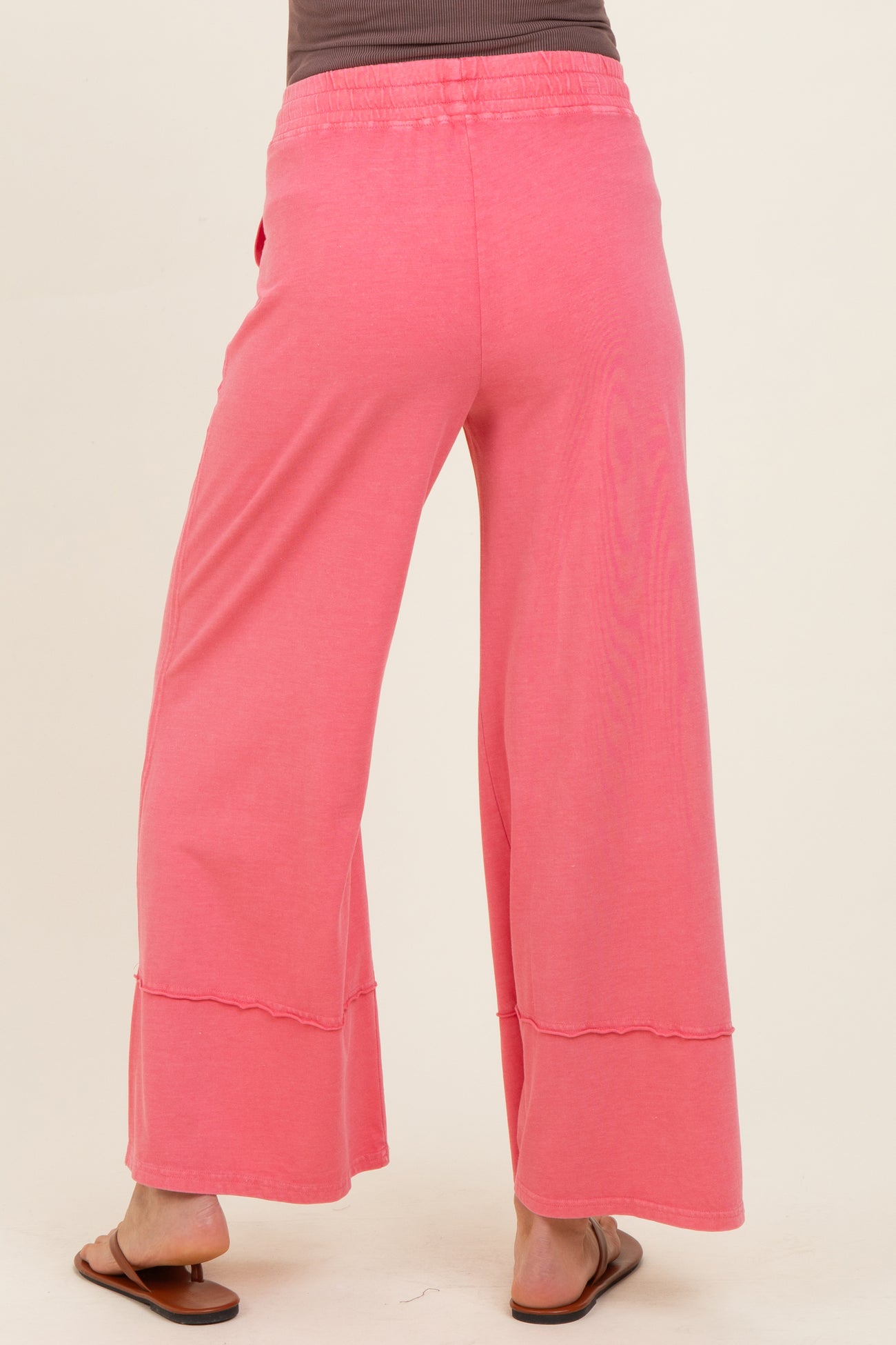 woman wearing pink maternity wide-leg pants, shown from the back, featuring a relaxed fit and comfortable waistband