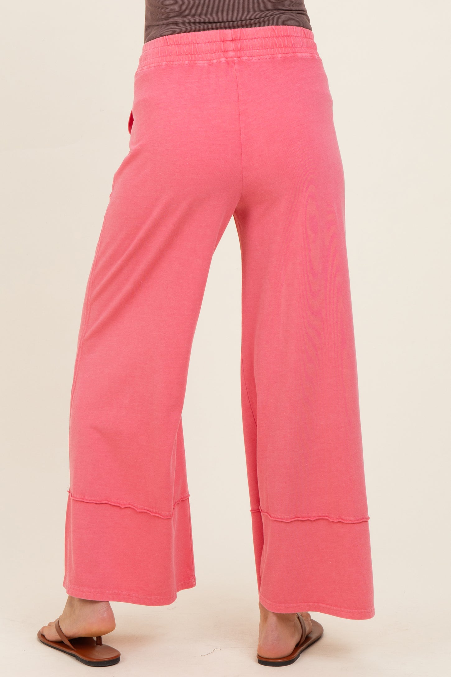 woman wearing pink maternity wide-leg pants, shown from the back, featuring a relaxed fit and comfortable waistband