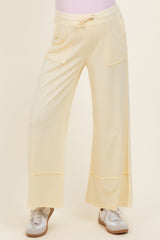 maternity wear in a soft yellow color featuring wide leg design and front pockets, styled with sneakers