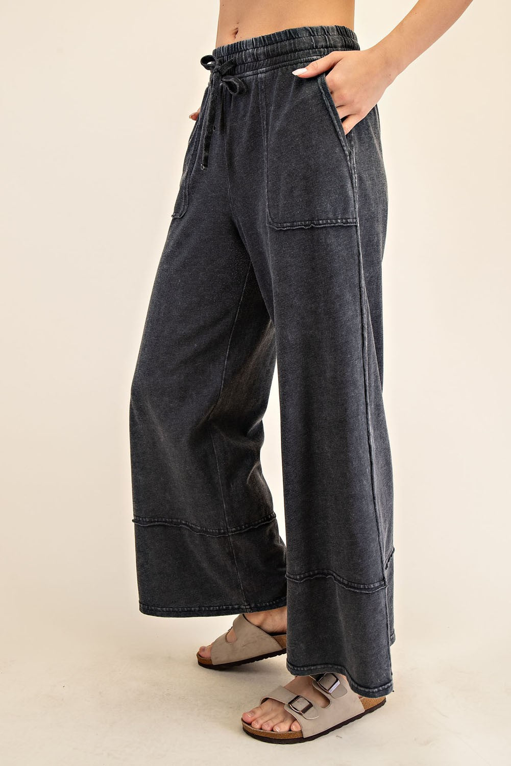 woman wearing dark gray wide leg lounge pants with side pockets and an elastic waistband