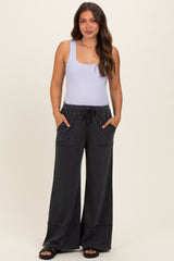 woman wearing a light purple tank top and dark gray wide-leg maternity pants with pockets and drawstring waist
