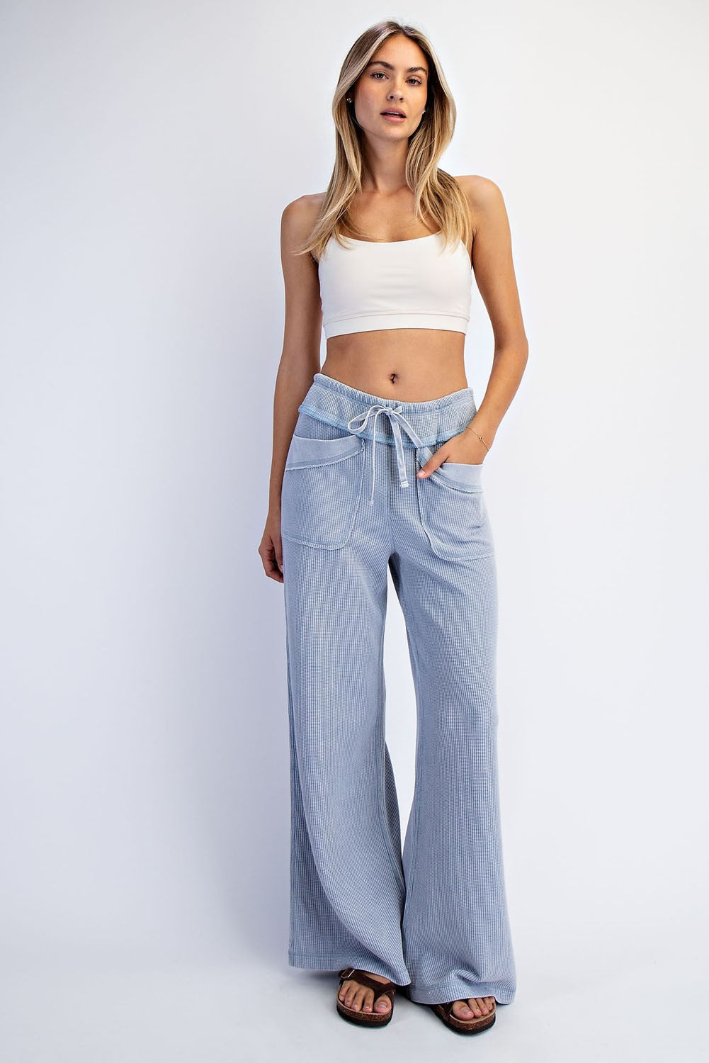 woman wearing a white cropped tank top and light blue wide-leg pants with pockets and drawstring waist