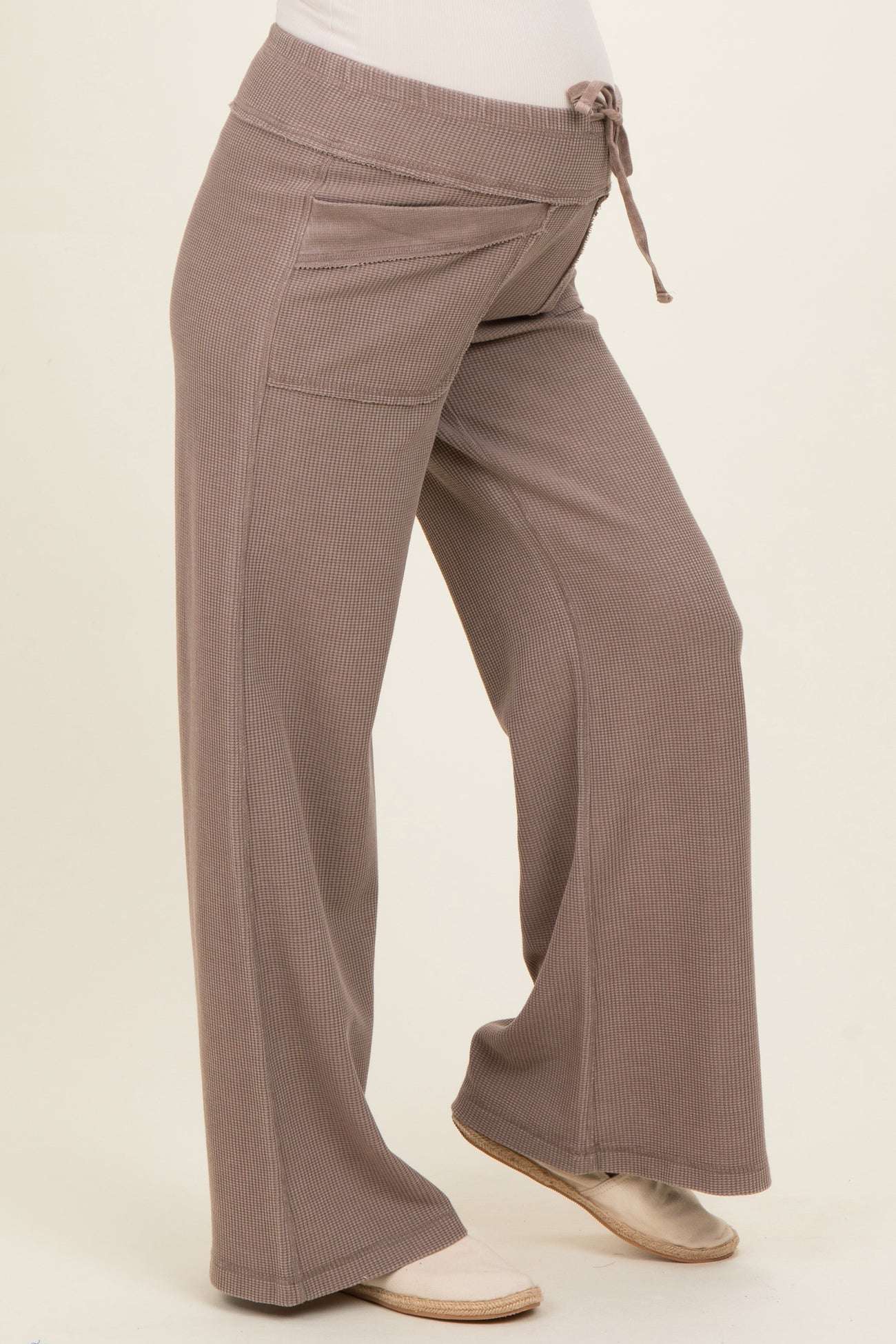 woman wearing light brown ribbed maternity pants with a tie waist and a visible baby bump
