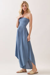 woman wearing a blue strapless maxi dress with a smocked bodice and high-low hemline