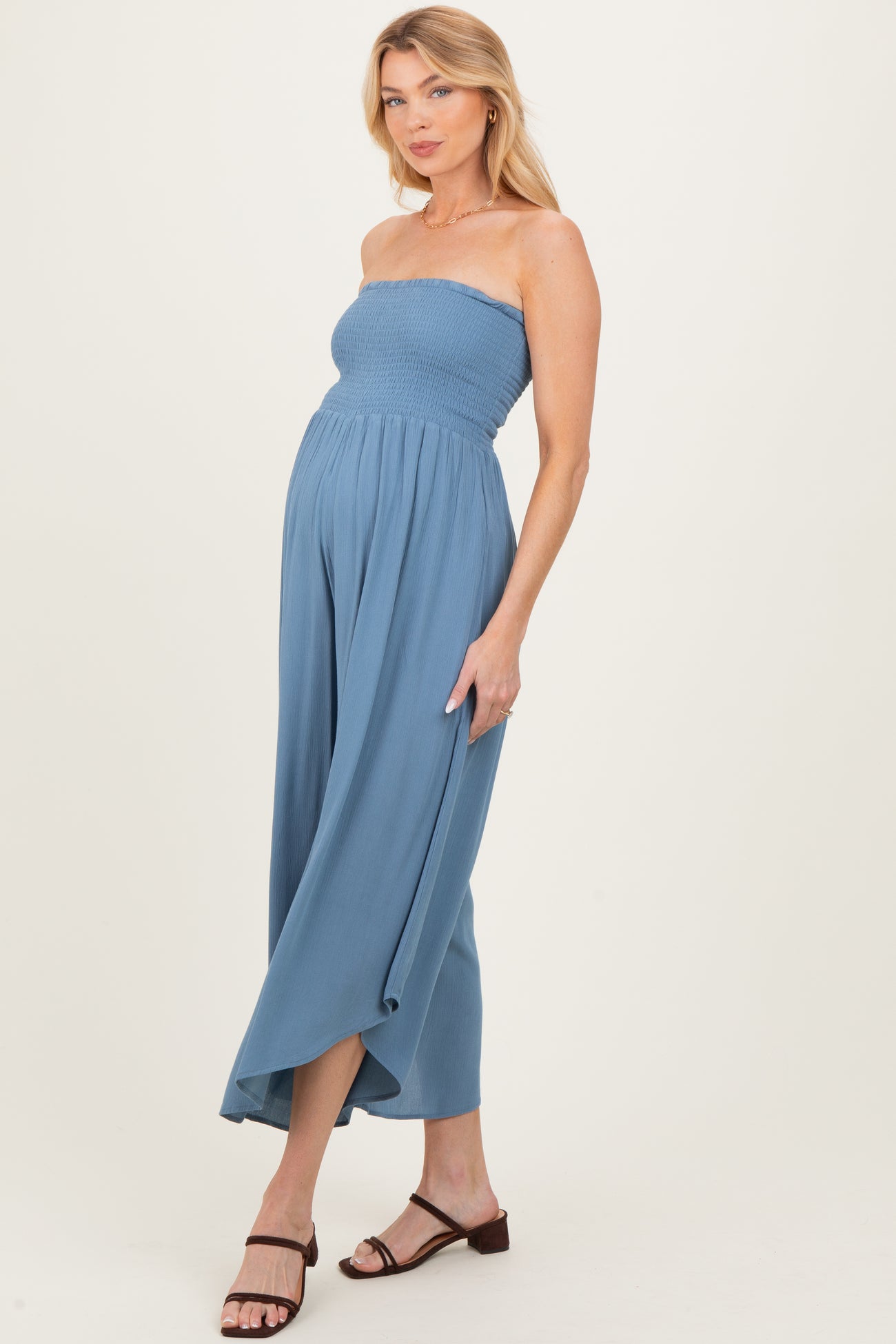 woman wearing a light blue strapless maternity jumpsuit, showcasing her baby bump with a flowy mid-calf skirt