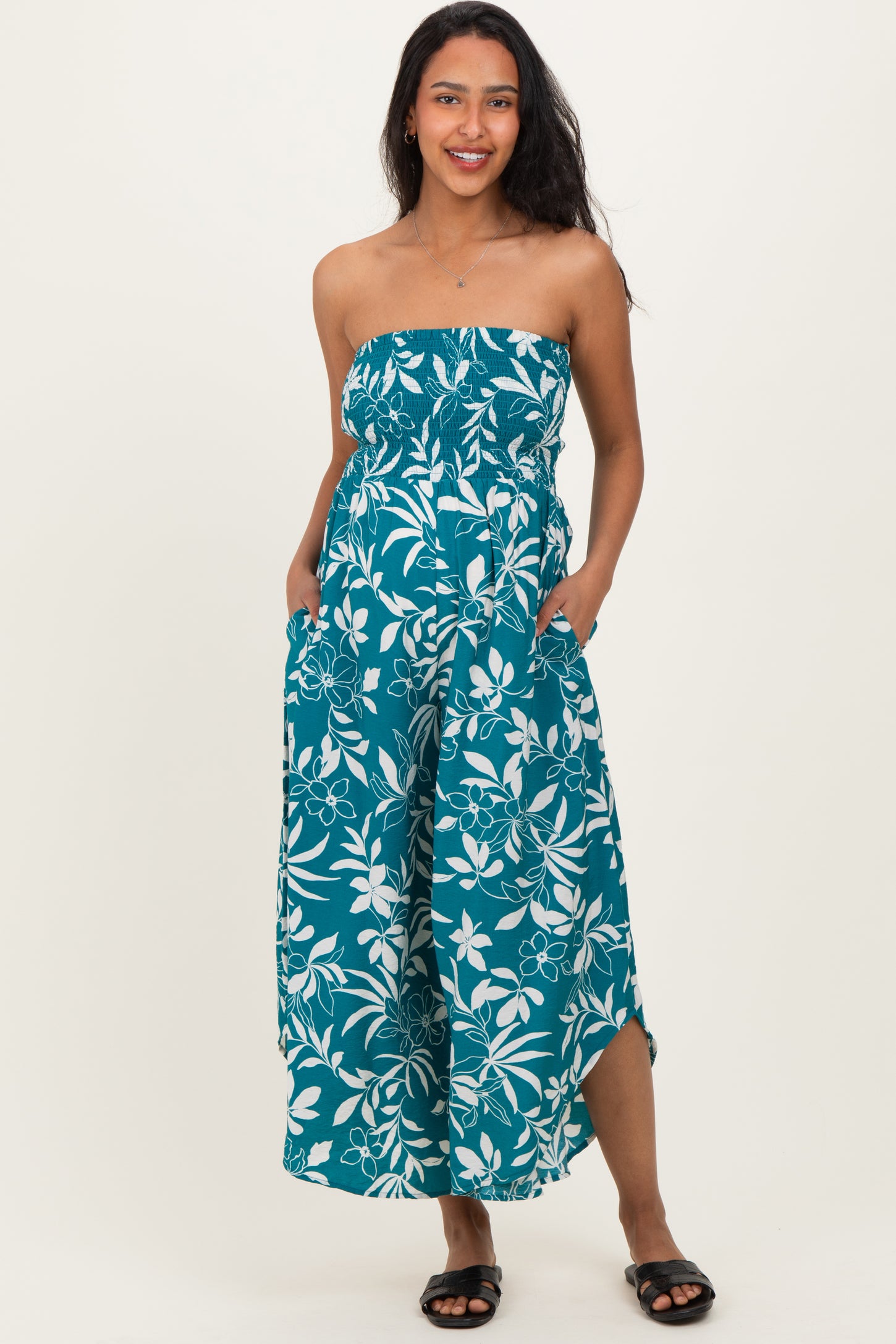 woman wearing a strapless teal floral maternity maxi dress with pockets and a fitted bodice, showcasing her baby bump