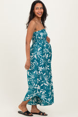woman wearing a teal strapless maternity dress with white floral pattern and holding her baby bump