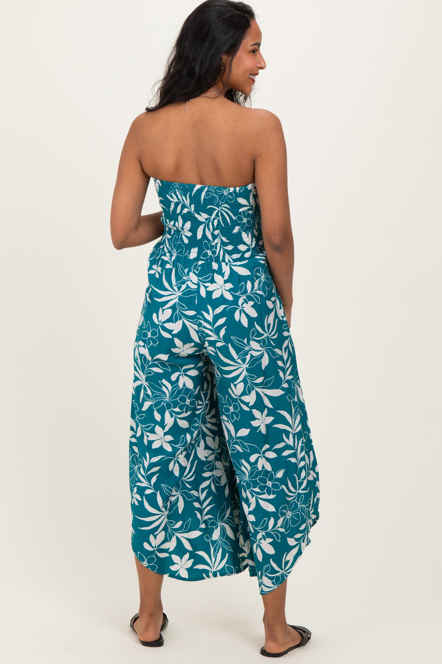 woman wearing a teal floral print maternity jumpsuit with a strapless top and wide leg pants