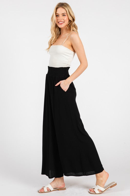 woman wearing a white camisole top and black wide-leg pants with side pockets