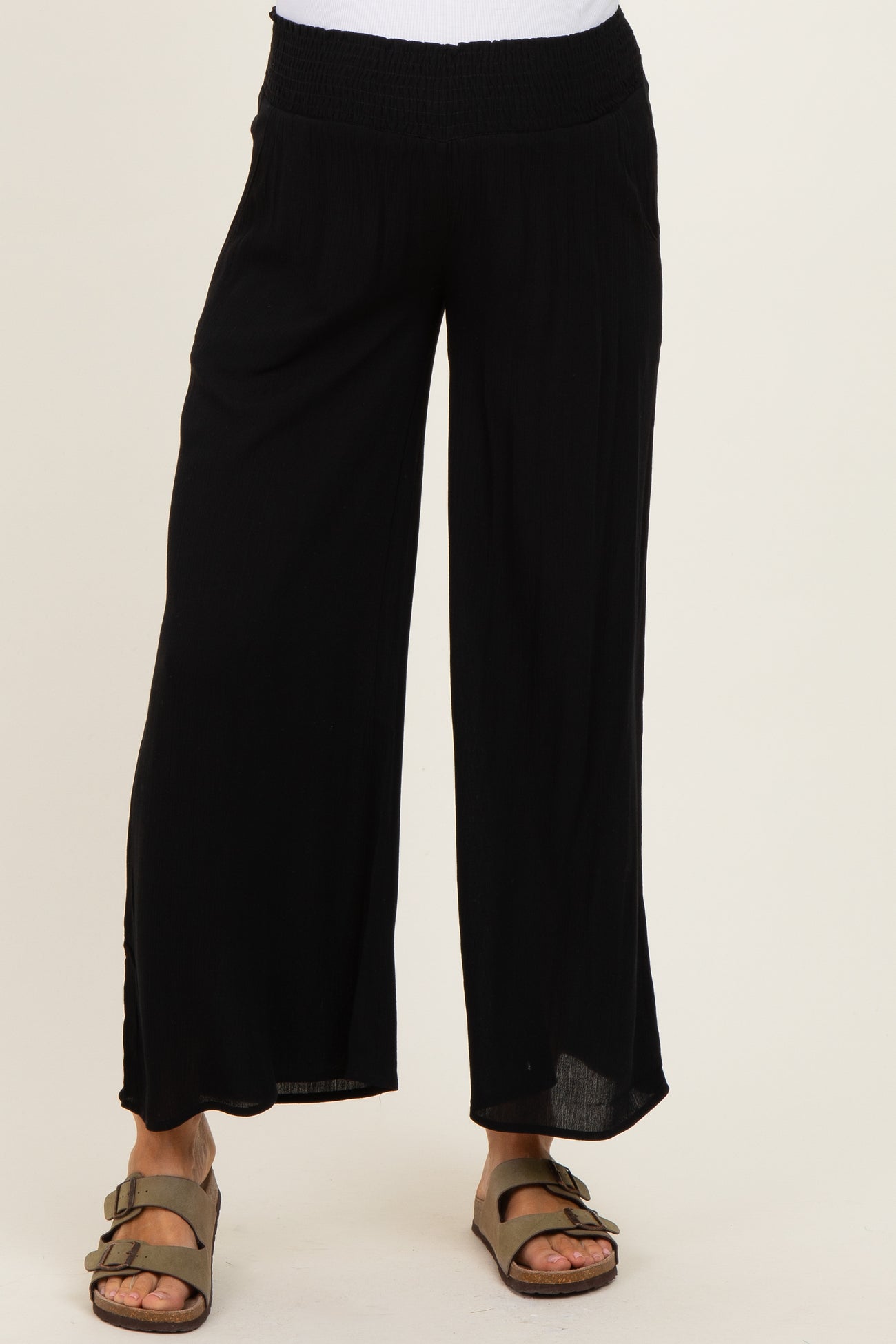 woman wearing black loose-fitting maternity pants with a smocked waistband and wide legs