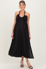 woman wearing a black halter neck maternity maxi dress with a flowing silhouette and visible baby bump