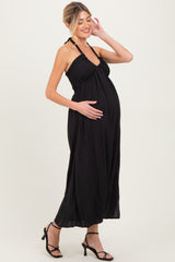 woman wearing a black halter neck maternity maxi dress and holding her baby bump