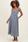 woman wearing a navy and white gingham maternity dress with smocked bodice and tie straps, showing her baby bump