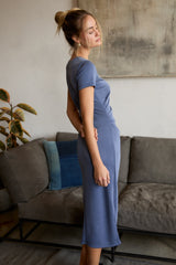 woman wearing a fitted slate blue midi dress, standing sideways with her hand on her hip