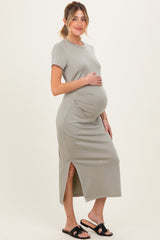 woman wearing a light green short sleeve maternity dress with side slits and holding her baby bump
