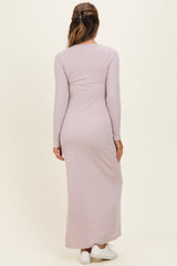 woman wearing a long sleeve light pink ribbed maxi dress, standing with her back to the camera