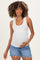 woman wearing a white ribbed maternity tank top and denim shorts, holding her baby bump
